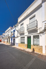 Nerja town, a resort of The Costa del Sol seaside region in Andalusia in the south of Spain. Sunny street scene with whitewashed houses and balconies. Cobblestone street and clear blue sky.