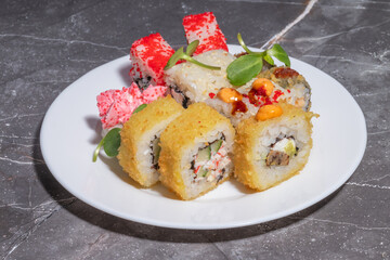 Sushi rolls with various toppings, including fried tempura, tobiko, and spicy sauce, elegantly plated.