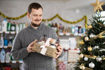 Positive man choosing present for New Year in small store