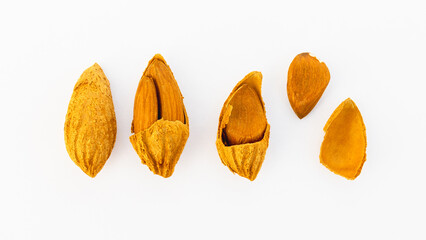 A close-up of almonds in various stages of being cracked open, showing the shells and nuts inside,...