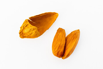 A close-up of almonds in various stages of being cracked open, showing the shells and nuts inside,...