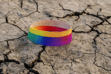 A Rainbow colored bandage on cracked earth symbolizes healing and recovery, representing rights activism and pride month