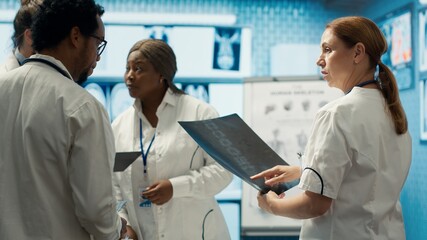 Fototapeta premium Professional doctors review hospital records and treatment plans in a private clinic to ensure good medical insurance services. Diverse experts analyzing test results for solutions. Camera A.
