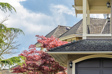 Top of luxury house with shingle roof, red and yellow trees and nice windows in Summer in...