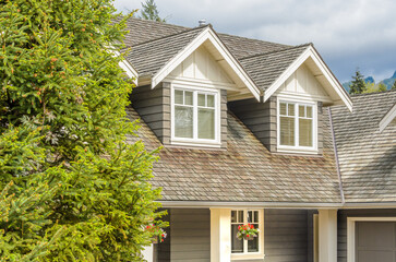 Top of luxury house with shingle roof, red and yellow trees and nice windows in Summer in Vancouver, Canada, North America. Day time on June 2024.