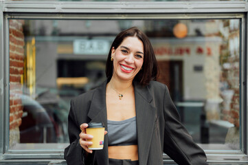 Businesswoman smiling and holding coffee outside cafe