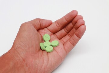 Hand holding Green Medicine Tablet on white background