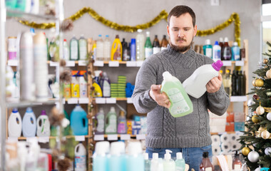 Casual young man in knitted sweater shopping in household goods store during Christmas holidays,...