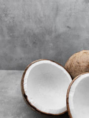 Two halves of fresh coconut resting on gray surface. Copy space, banner