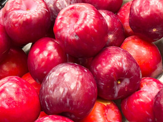 Bright red plums close-up: fresh juicy fruits in abundance