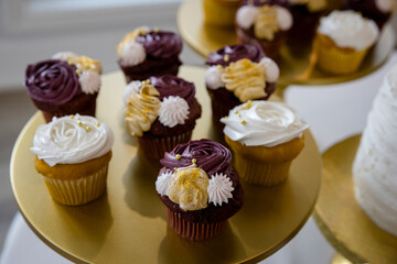 Elegant purple and white frosted cupcakes on gold display plates for wedding reception