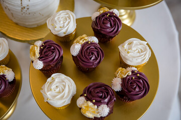 Elegant purple and white frosted cupcakes on gold display plates for wedding reception
