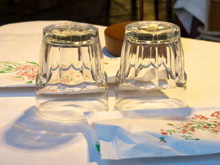 Upside-down glasses on table with floral napkins and wrapper in sunlit setting