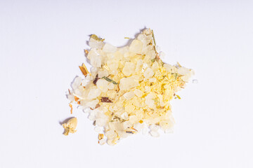 A star-shaped arrangement of yellowish bath salts with herbal elements on a white background.