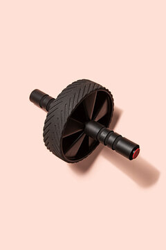 Ab roller gym equipment on a pink background