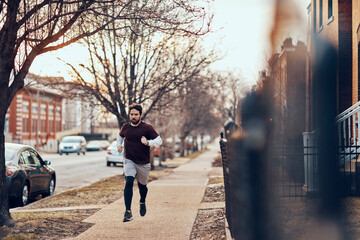 Young man jogging in a town on a street