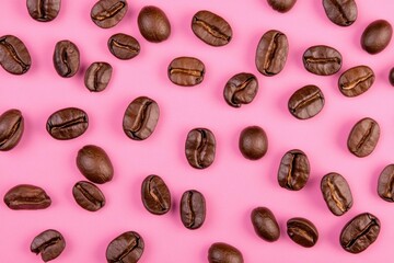 Obraz premium Coffee Beans on Pink Background A vibrant arrangement of brown coffee beans creating an energetic mood, ideal for coffee related concepts and culinary projects