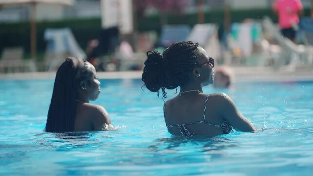 Braided hair group of african black friends enjoying a pool party on a sunny summer day dancing in slow motion