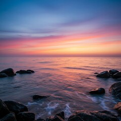 Naklejka premium A realistic seascape at sunrise with gentle waves, rocky shoreline, and vibrant sky colors.