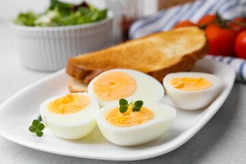 Hard boiled eggs with bread on light table, closeup