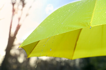 Open yellow umbrella under pouring rain outdoors, closeup
