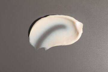 Cream on grey background, top view. Sample of cosmetic product