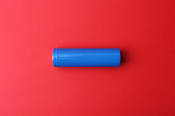 One AA cell battery on red background, top view