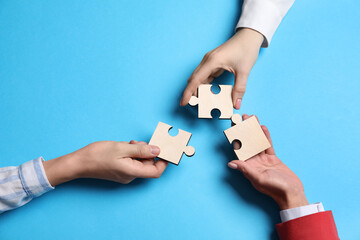Business strategy and teamwork concept. Partners with different puzzle pieces on light blue...