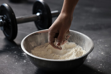 Woman applying talcum powder onto her hands above bowl before training in gym, closeup