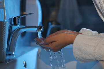 Woman washing her face over sink in bathroom, closeup