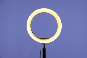 Ring lamp on stand against purple background