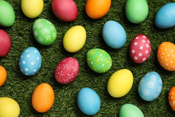 Beautiful decorated Easter eggs on green grass, flat lay