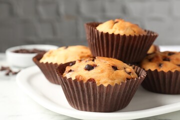 Delicious muffin with chocolate chips on table, closeup