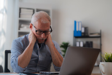 Tired businessman having neck pain while using laptop computer, senior office worker massaging his neck, feeling discomfort after long time working on computer, health problem concept