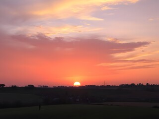 Fototapeta premium Sunset Over a Serene Village with Orange and Purple Skies, Tranquil Atmosphere