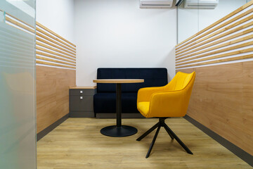 Cozy seating area with yellow chair, black sofa, and round wooden table
