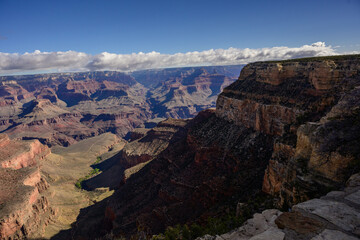 Grand Canyon rock layers landscape with sunshine and white clouds on clear day