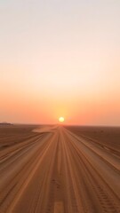 Naklejka premium Sunset Over Dusty Desert Roads Leading to an Endless Horizon with Soft Pink and Yellow Sky