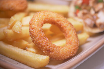 Crispy onion rings and golden fries served on a wooden plate