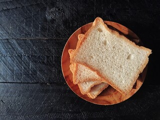 Pile of slices bread on black wooden table background with top view angle, copy space 