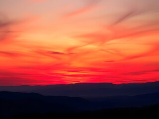 Obraz premium Sunrise Over Valley with Fiery Red and Orange Sky, Illuminating the Landscape