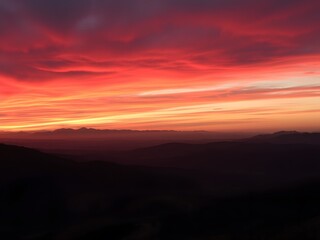 Obraz premium Stunning Red and Orange Sunrise Lighting Up the Valley and Mountains in the Background