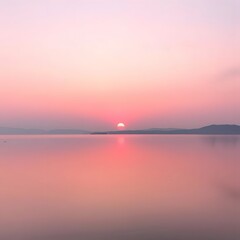 Fototapeta premium A lake bathed in soft pink and lavender sunset light, with the sun setting behind distant hills, creating soft shadows across the