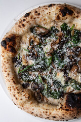 a close up of a mushroom pizza with spinach and parmesan cheese