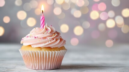 Delicious pink frosted cupcake with a lit candle on a softly blurred background with colorful bokeh lights
