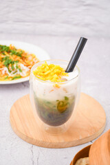 glass of cendol ice with jackfruit topping, Cendol is an iced sweet dessert that contains droplets of green rice flour jelly, coconut milk and palm sugar syrup. It is commonly found in Indonesia