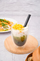 glass of cendol ice with jackfruit topping, Cendol is an iced sweet dessert that contains droplets of green rice flour jelly, coconut milk and palm sugar syrup. It is commonly found in Indonesia