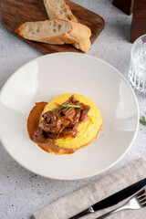 Stewed chicken liver with mashed potatoes and onions served on a white plate. Close-up