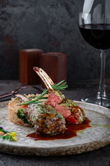  Grilled racks of lamb with demiglas sauce and vegetables and quinoa on a grey plate. Main course of lamb ribs, close up