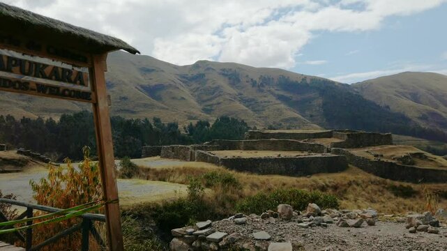 Entry gate and ancient stone ruins of Puka Pukara in Cusco, Peru. Pan right reveal shot of military fortress ruins on the old Pisac Cusco road